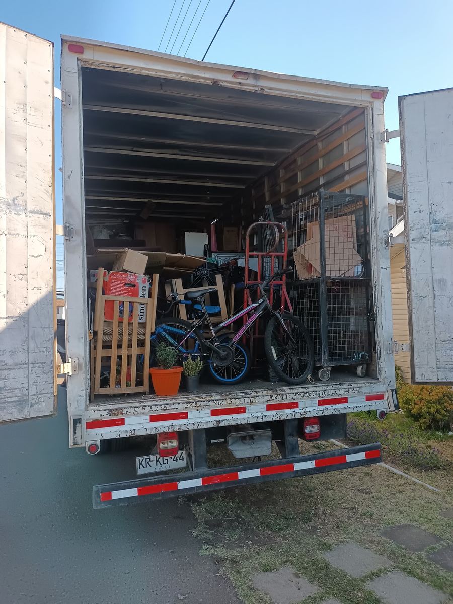 Camión abierto con muebles, cajas y bicicletas de una mudanza